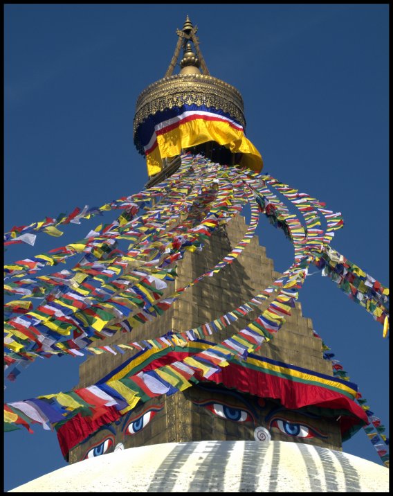 Prayer flags adding colour around Buddha's eyes on the stupa